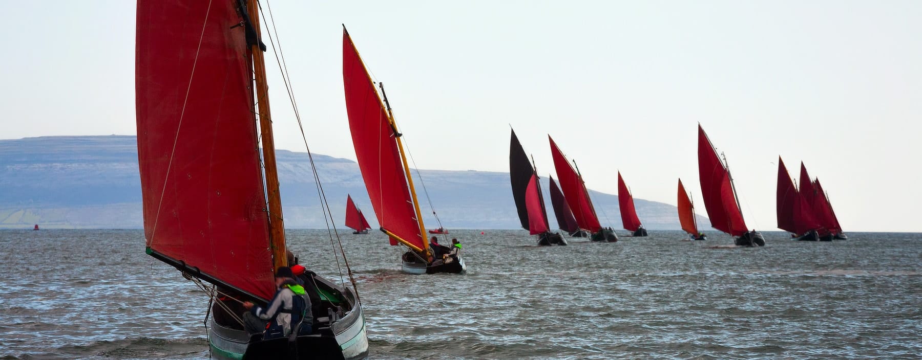 Galway hookers racing under red sails off the Connacht coast